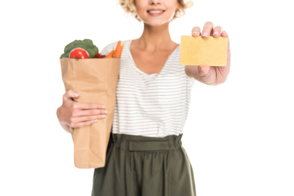 tiro recortado de mujer sosteniendo tarjeta de oro y bolsa de comestibles aislado en blanco
 - Foto, Imagen