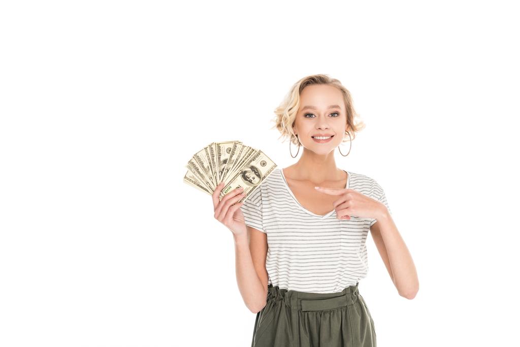 gyönyörű, fiatal nő tartja a dollár bankjegyek és mutató ujjával elszigetelt fehér mosolyogva - Fotó, kép