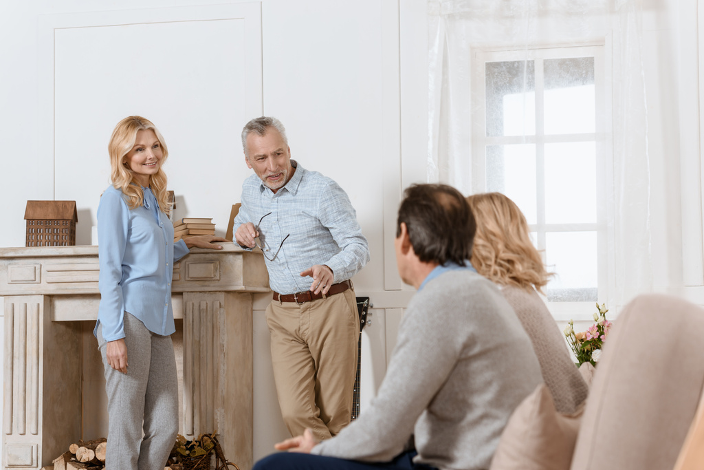 Vanhemmat miehet ja naiset, joilla on ystävällinen keskustelu kevyessä viihtyisässä huoneessa
 - Valokuva, kuva