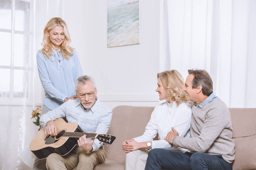 Orta yaşlı erkekler ve kadınlar gitar müzik oturma odasında - Fotoğraf, Görsel