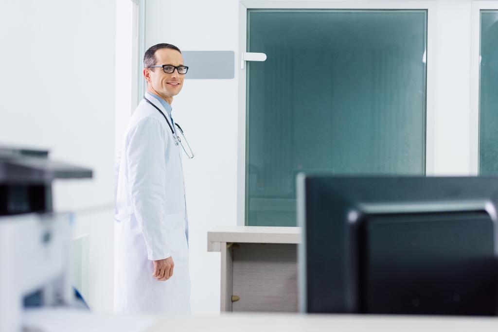 мужчина улыбается доктор в белом халате со стетоскопом в больнице
 - Фото, изображение
