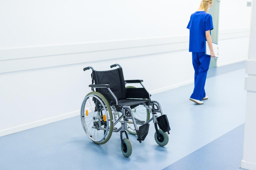 chirurgo donna nel corridoio dell'ospedale, sedia a rotelle in primo piano
 - Foto, immagini