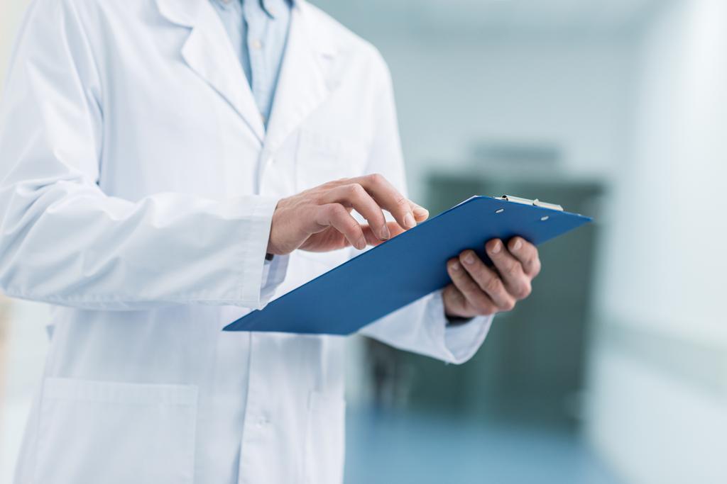 обрезанный взгляд врача в белом халате проведение диагностики в больнице
 - Фото, изображение