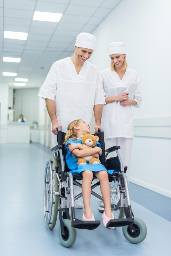 lääkärit ja pieni potilas nallekarhu pyörätuolissa sairaalassa
 - Valokuva, kuva