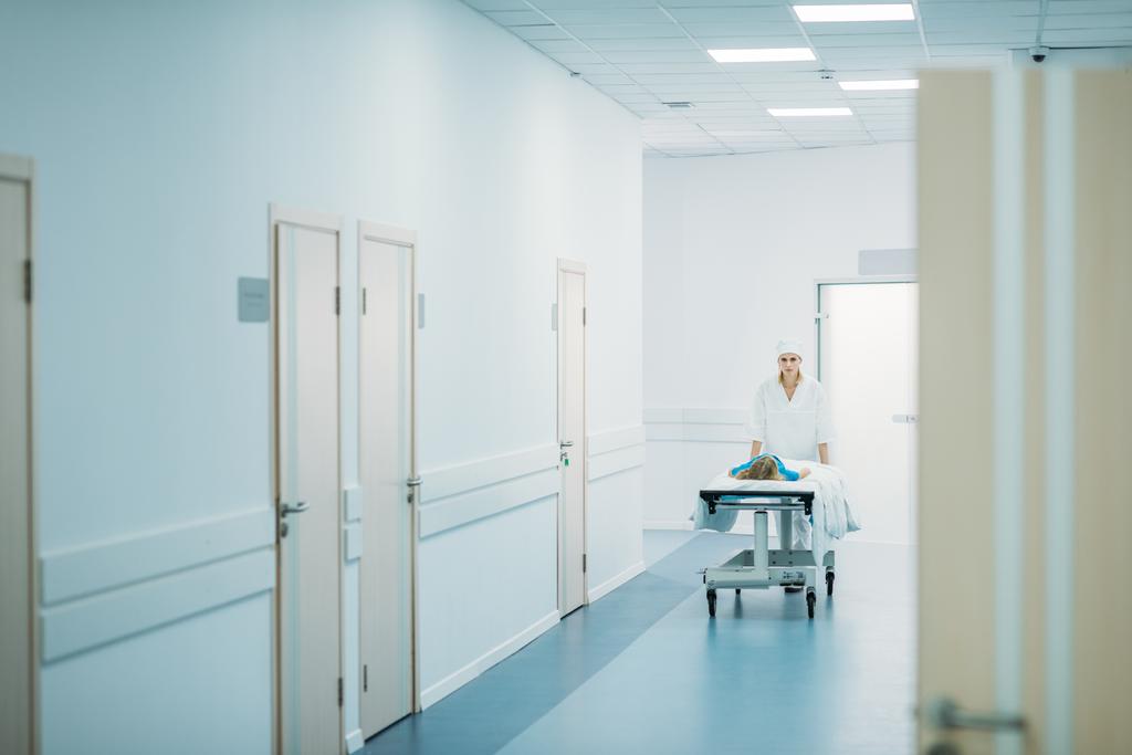 médecin déplaçant le patient préscolaire sur civière médicale dans le couloir
  - Photo, image