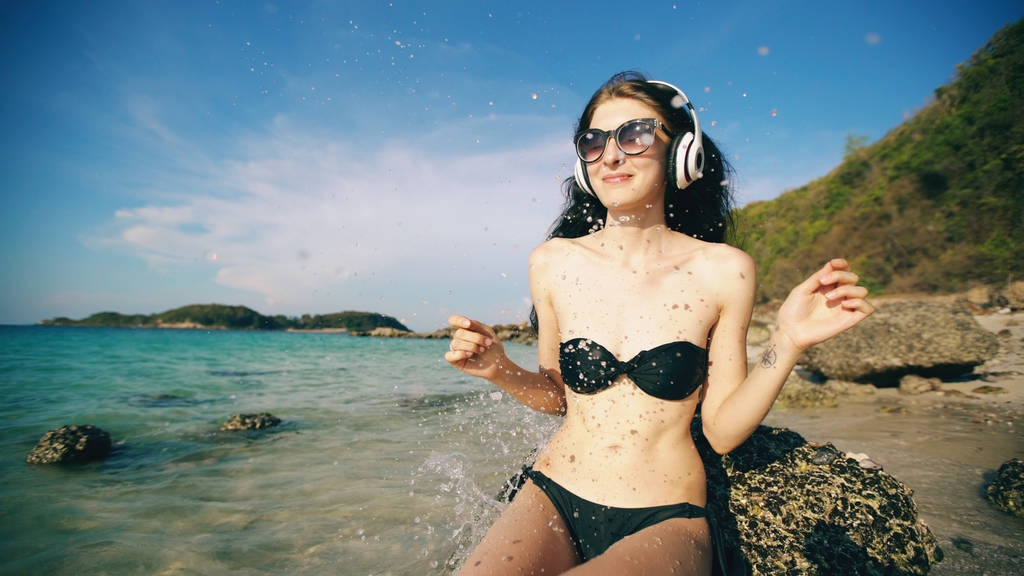 Deniz kenarında plajda kablosuz kulaklıklar müzik dinlerken mutlu güzel kadın - Fotoğraf, Görsel