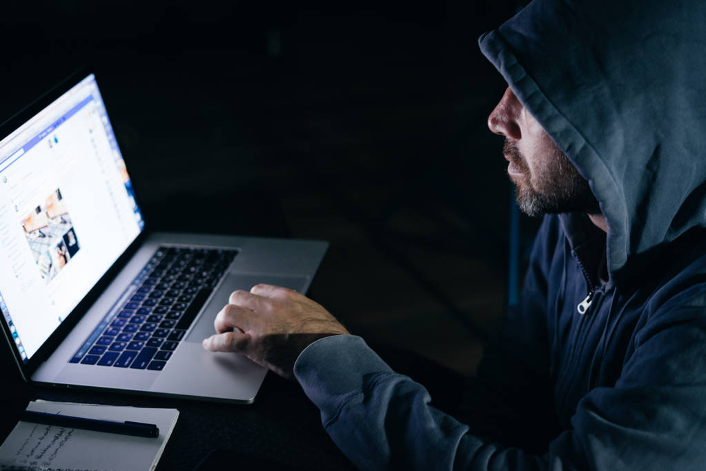tajemniczy mężczyzna hacker, ukrywa jego twarz pod maską, robi coś nielegalnego na laptopie - Zdjęcie, obraz