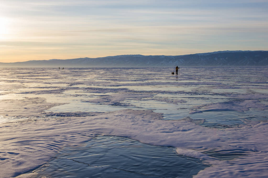 senderista masculino con mochila caminando sobre la superficie del agua helada contra colinas en la orilla, Rusia, lago baikal
    - Foto, imagen