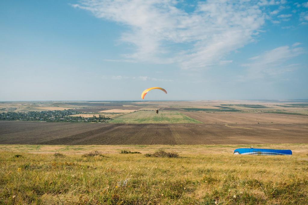 Laskuvarjohyppääjät liitävät sinisellä taivaalla Krimin maiseman yllä, Ukraina, toukokuu 2013
 - Valokuva, kuva