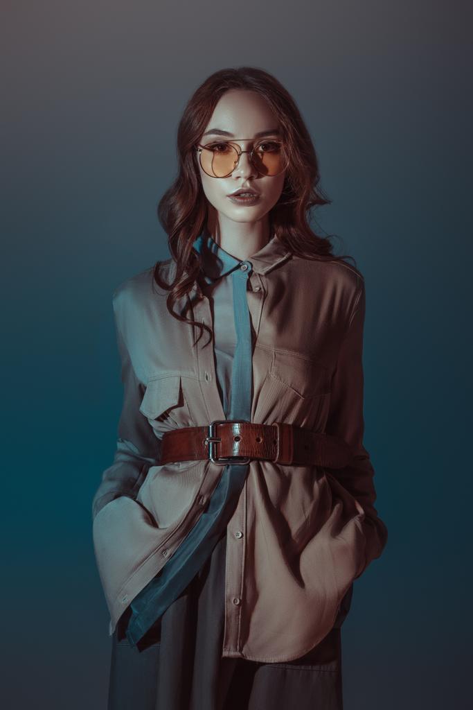 modny dziewczyna pozuje w jesienny strój i okulary przeciwsłoneczne, na szarym tle - Zdjęcie, obraz
