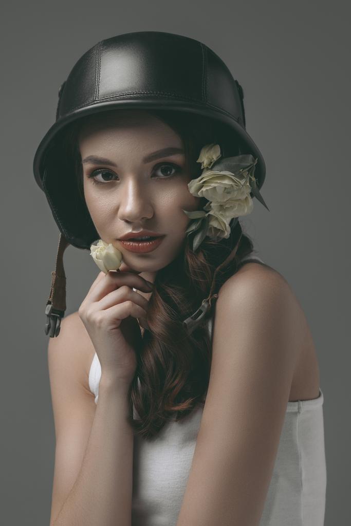 スタイリッシュな若いモデルと白い花、グレーに分離された軍用ヘルメット - 写真・画像