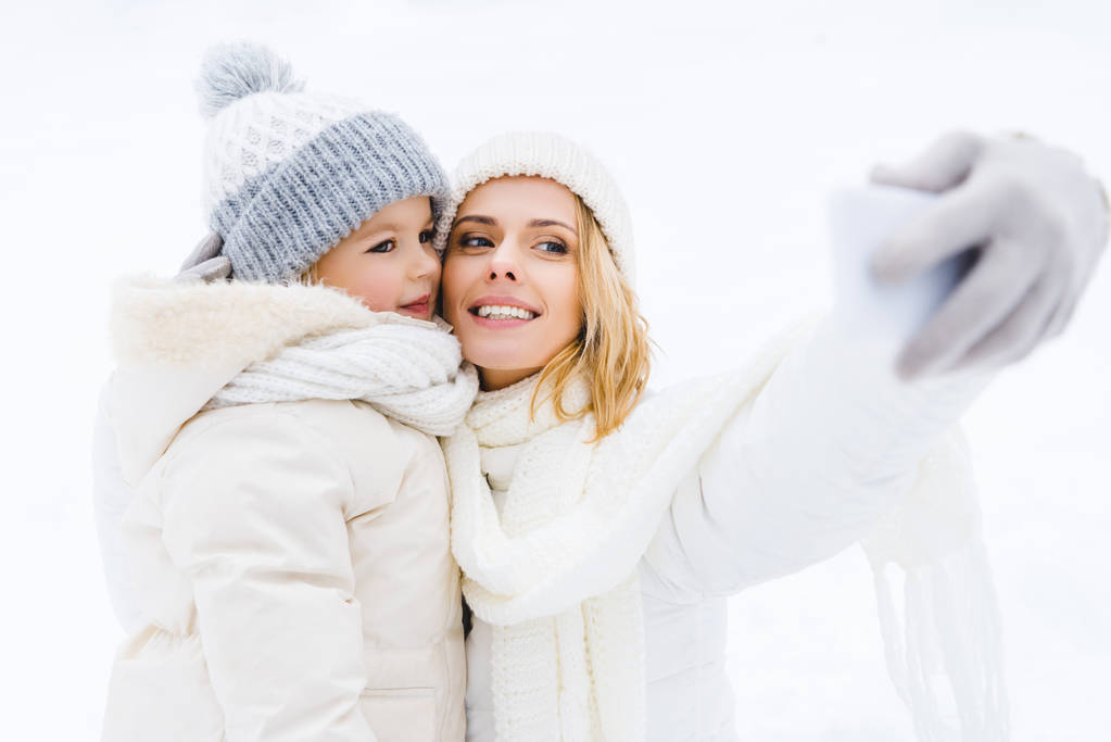 happy mother and daughter taking selfie in winter park - Photo, Image