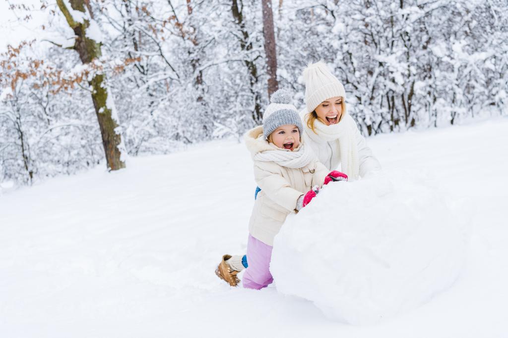 mãe feliz e filha pequena bonito fazendo boneco de neve juntos no parque de inverno
 - Foto, Imagem