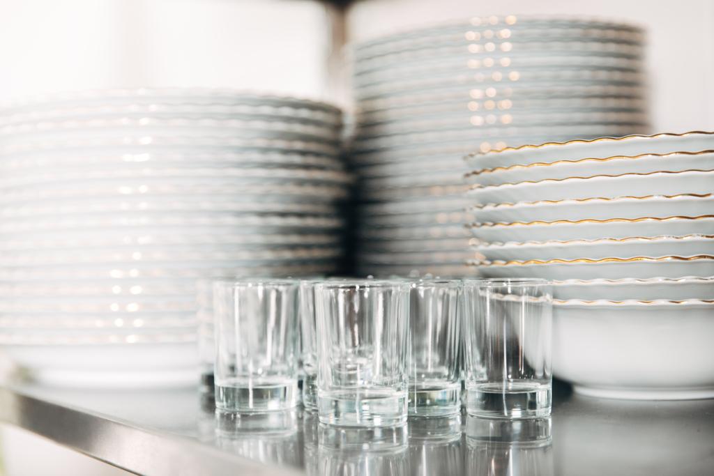 Nahaufnahme von gestapeltem sauberem Geschirr und Gläsern im Restaurant - Foto, Bild