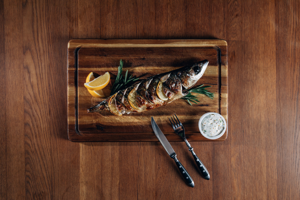 vue du dessus de délicieux poissons grillés au citron sur une planche en bois
 - Photo, image