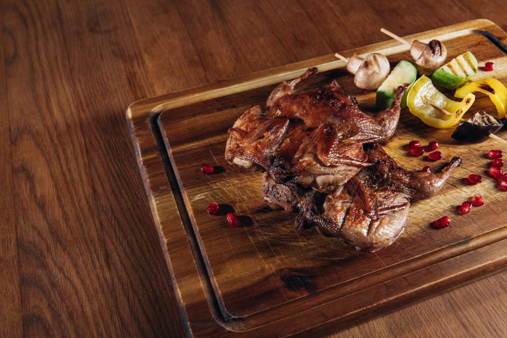 close-up shot of roasted quail with vegetables served on wooden board - Photo, Image