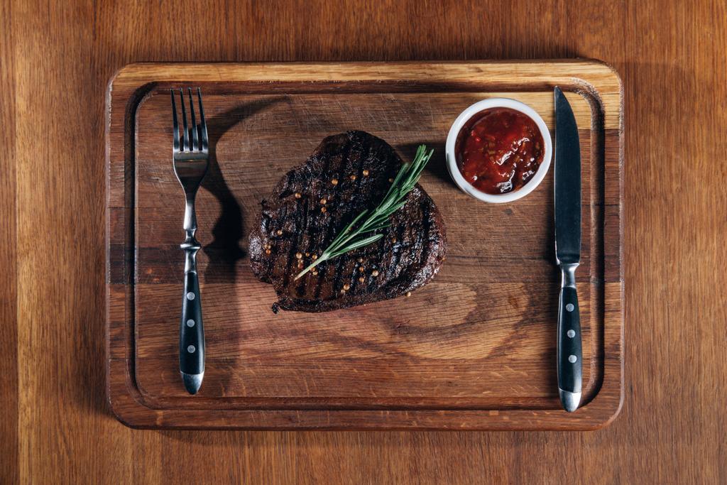 çatal bıçak takımı ve sos ızgara biftek üstten görünüm ahşap tahta üzerinde - Fotoğraf, Görsel