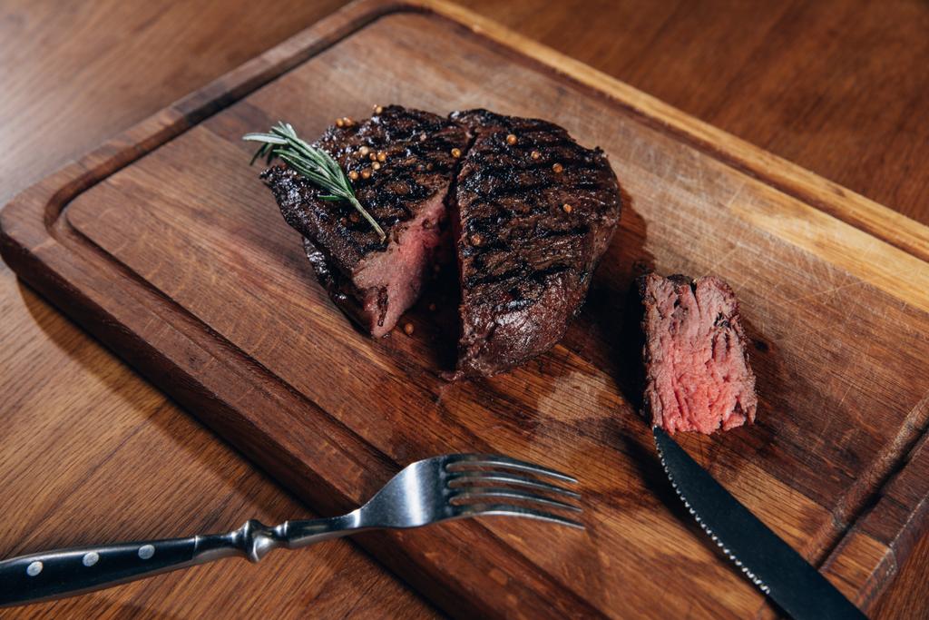 Nahaufnahme von köstlichem mittelseltenem gegrilltem Steak auf Holzbrett - Foto, Bild