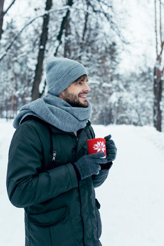 jeune homme tenant une tasse de café chaud dans les mains dans le parc d'hiver
 - Photo, image
