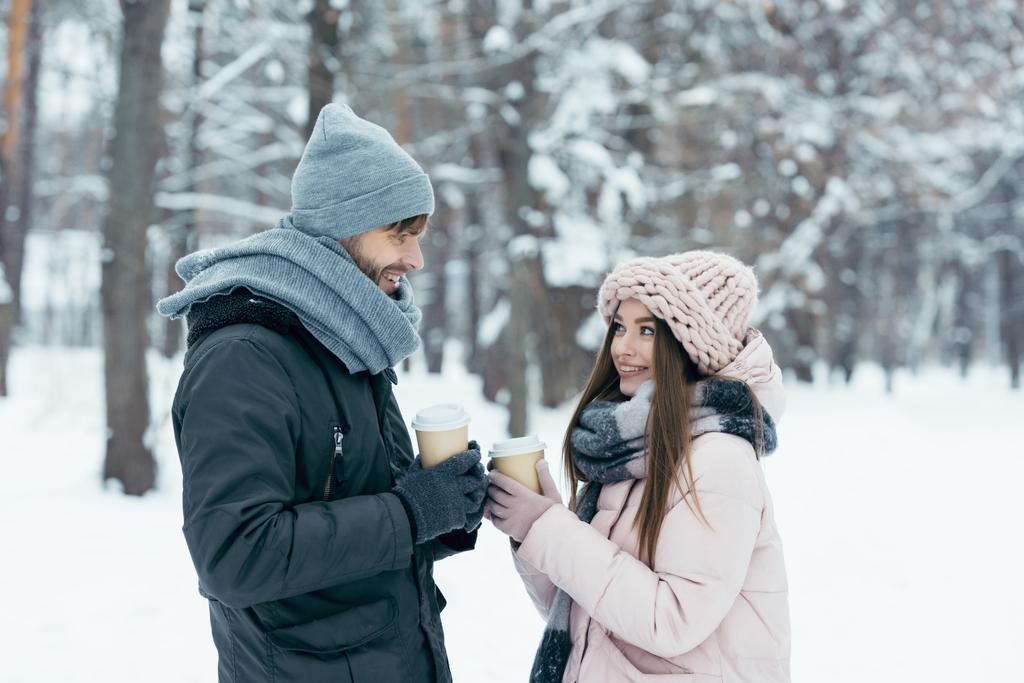vue latérale du couple joyeux avec café pour aller dans un parc enneigé
 - Photo, image
