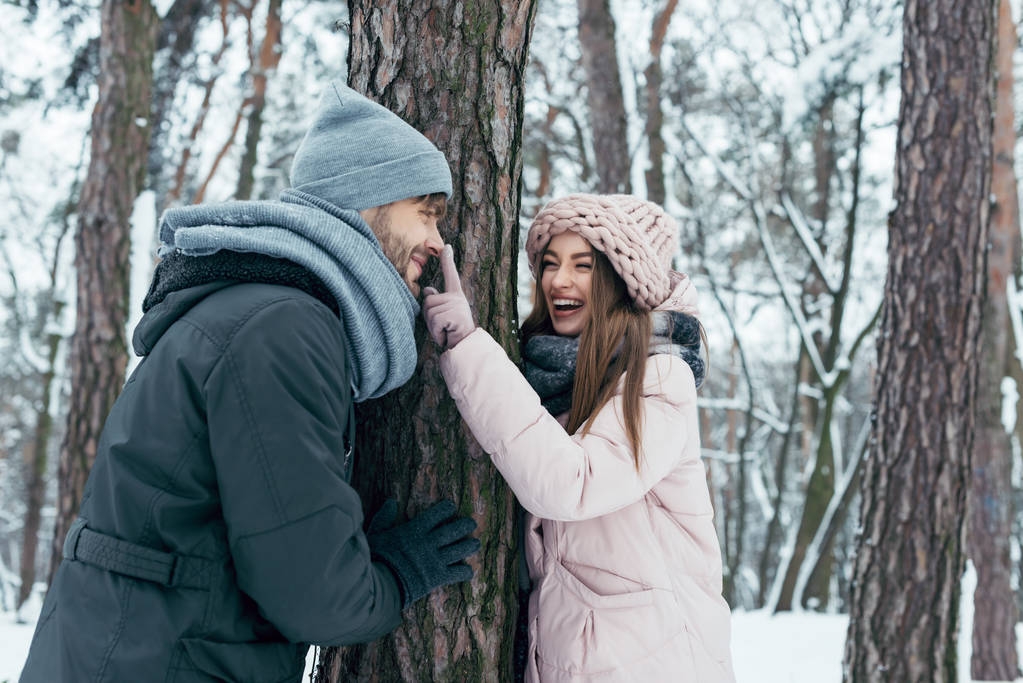 冬の公園の木に陽気な若いカップル立って - 写真・画像