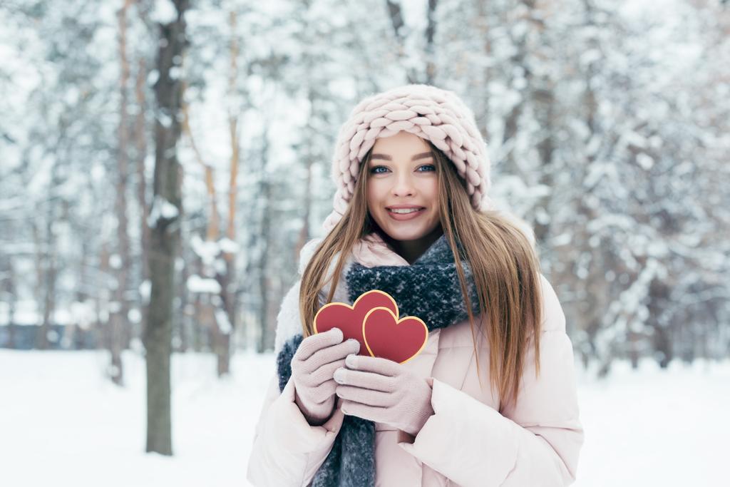 retrato de una hermosa joven con corazones en las manos mirando a la cámara en el parque nevado
 - Foto, Imagen