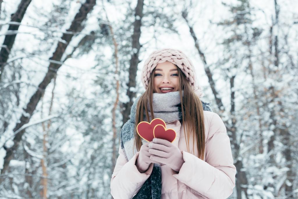 Portret z piękną, młodą kobietę z serca w ręce patrząc na kamery w snowy park - Zdjęcie, obraz