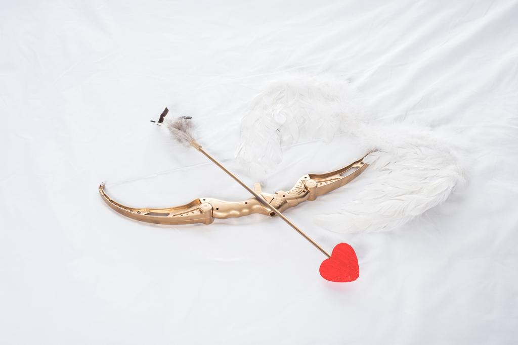 Beyaz yatakta üstten görünüm kanatları, yay ve ok - Fotoğraf, Görsel
