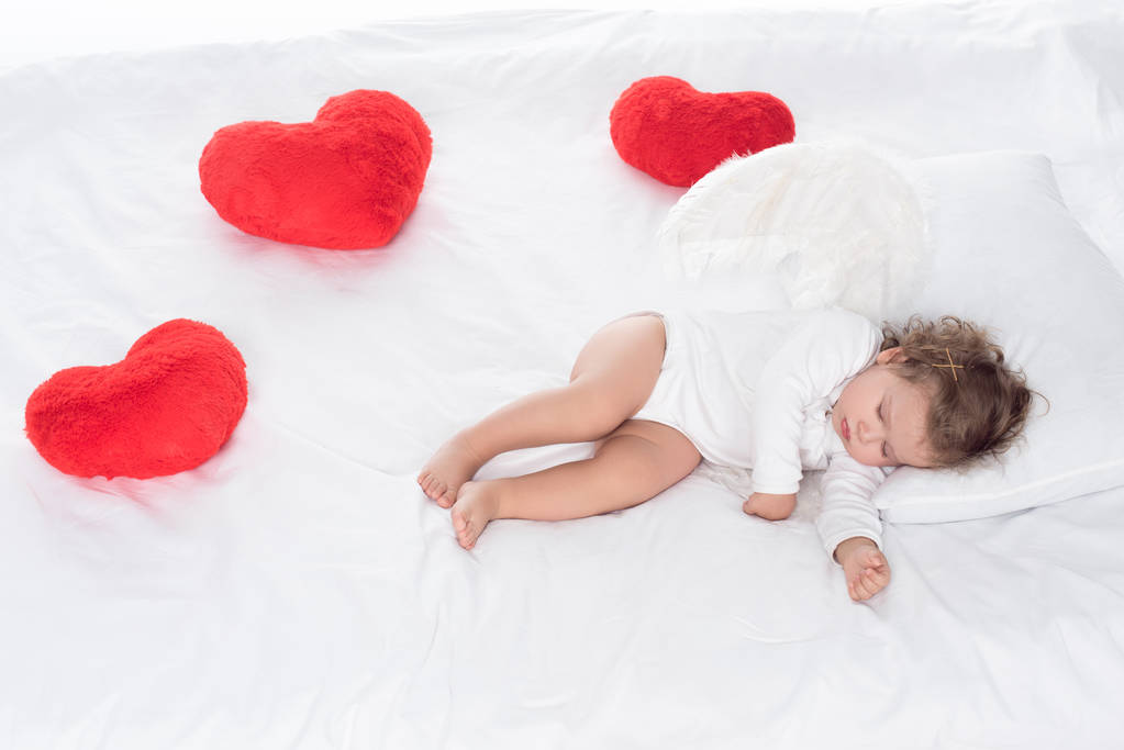 küçük melek kanatlı kalpleri ile yatakta yatarken  - Fotoğraf, Görsel