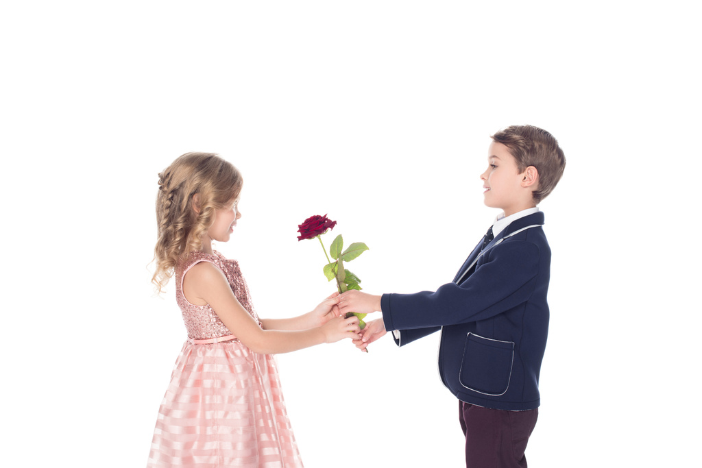 Seitenansicht von entzückenden stilvollen Kindern mit Rosenblume und Blick auf einander isoliert auf weiß - Foto, Bild
