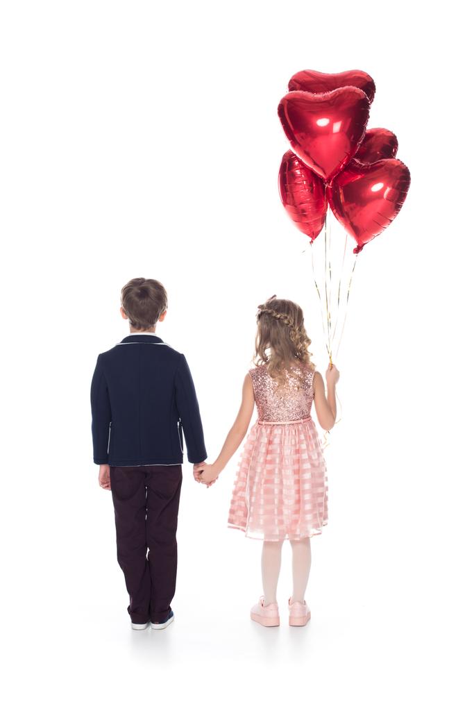vue arrière de mignons petits enfants avec des ballons en forme de coeur tenant les mains isolées sur blanc
  - Photo, image