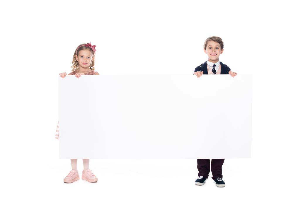 crianças bonitos segurando banner em branco e sorrindo para a câmera isolada no branco
 - Foto, Imagem