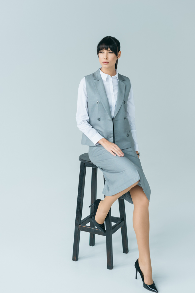 mujer de negocios sentada en la silla y mirando hacia otro lado en gris
 - Foto, Imagen