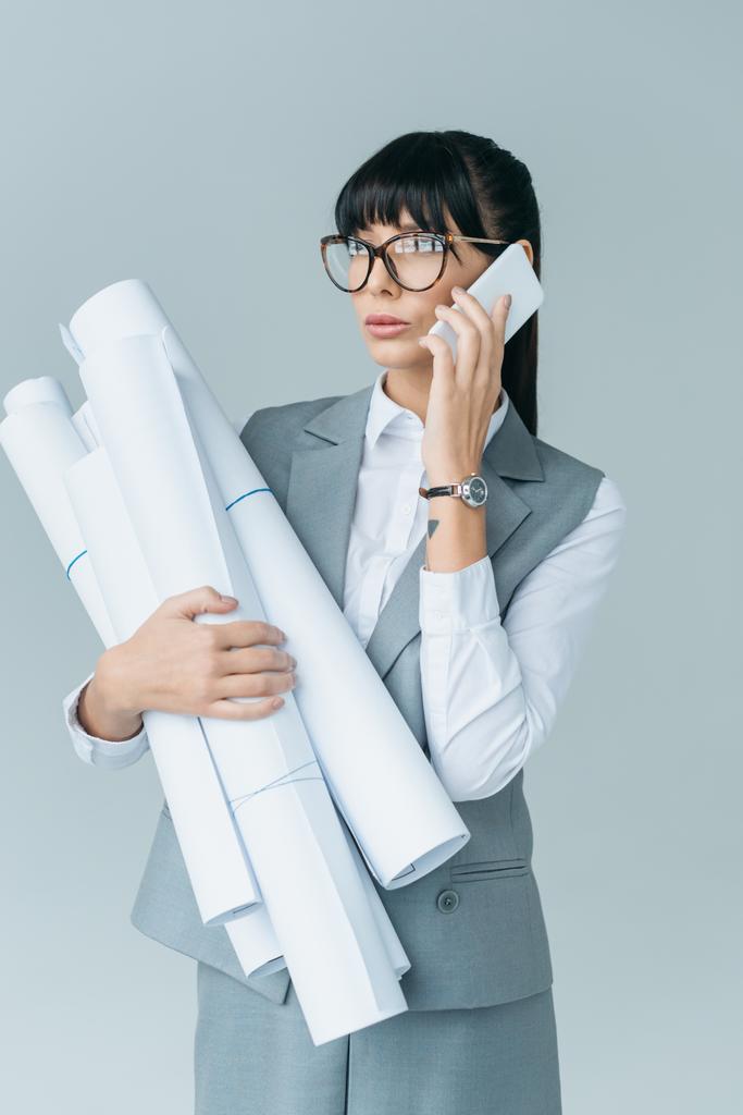 podnikatelka drží plány a mluví o smartphone izolované na šedé - Fotografie, Obrázek