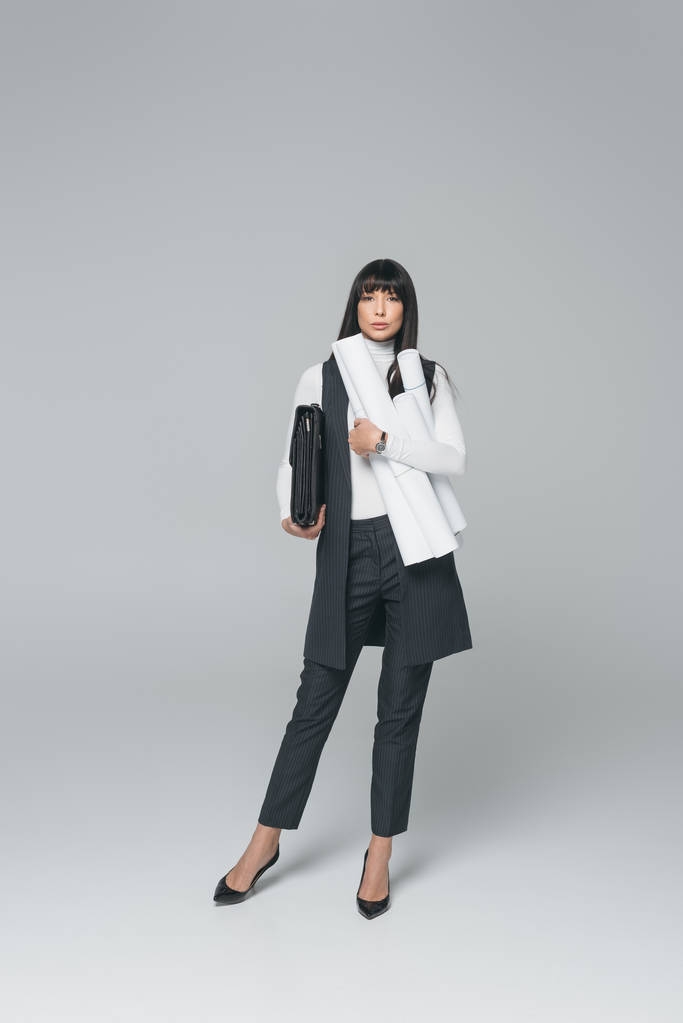 femme d'affaires debout avec mallette et plans sur gris
 - Photo, image
