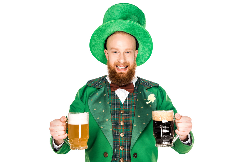 vrolijke bebaarde man in groene kostuum en hoed bedrijf glazen bier en kijken naar camera geïsoleerd op wit   - Foto, afbeelding