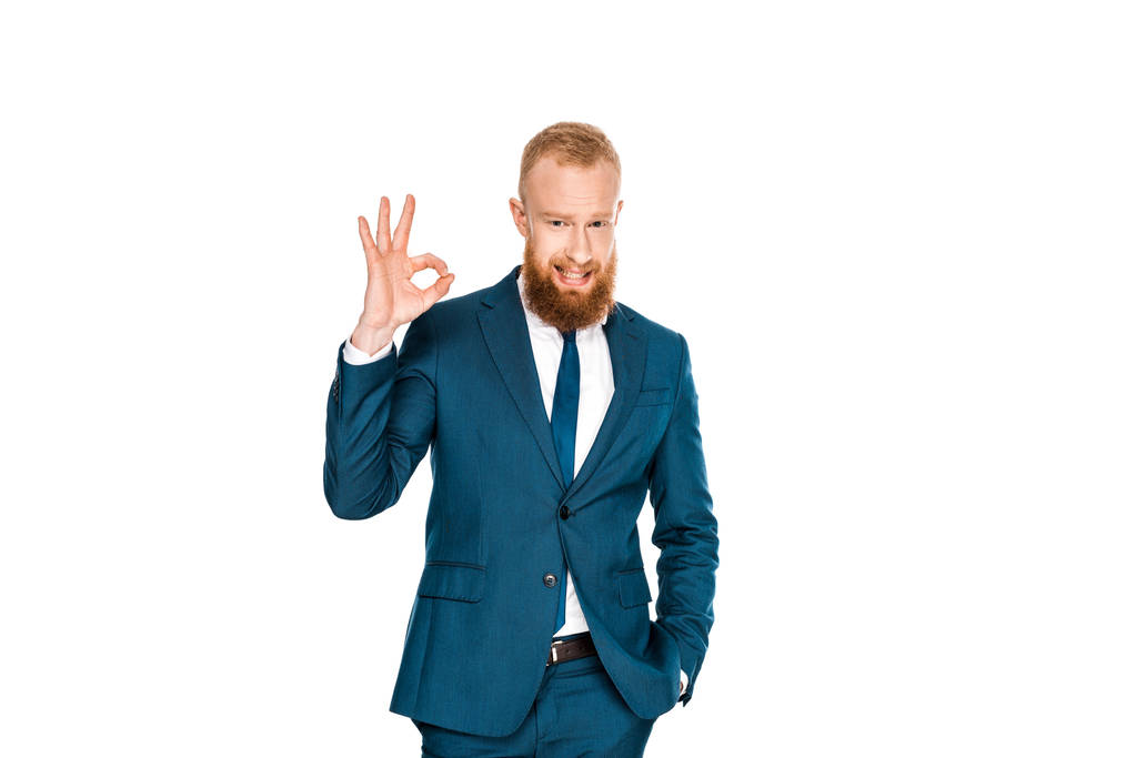 handsome bearded businessman standing with hand in pocket and showing ok sign isolated on white - Photo, Image