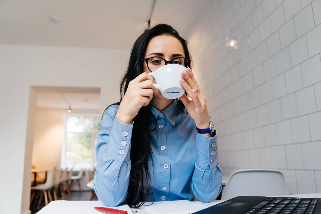 giovane studentessa in camicia blu e bicchieri beve caffè in un caffè dopo la scuola
 - Foto, immagini