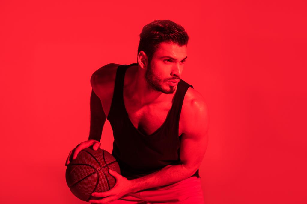 jovem desportista focado jogando basquete em contraste luz vermelha
  - Foto, Imagem