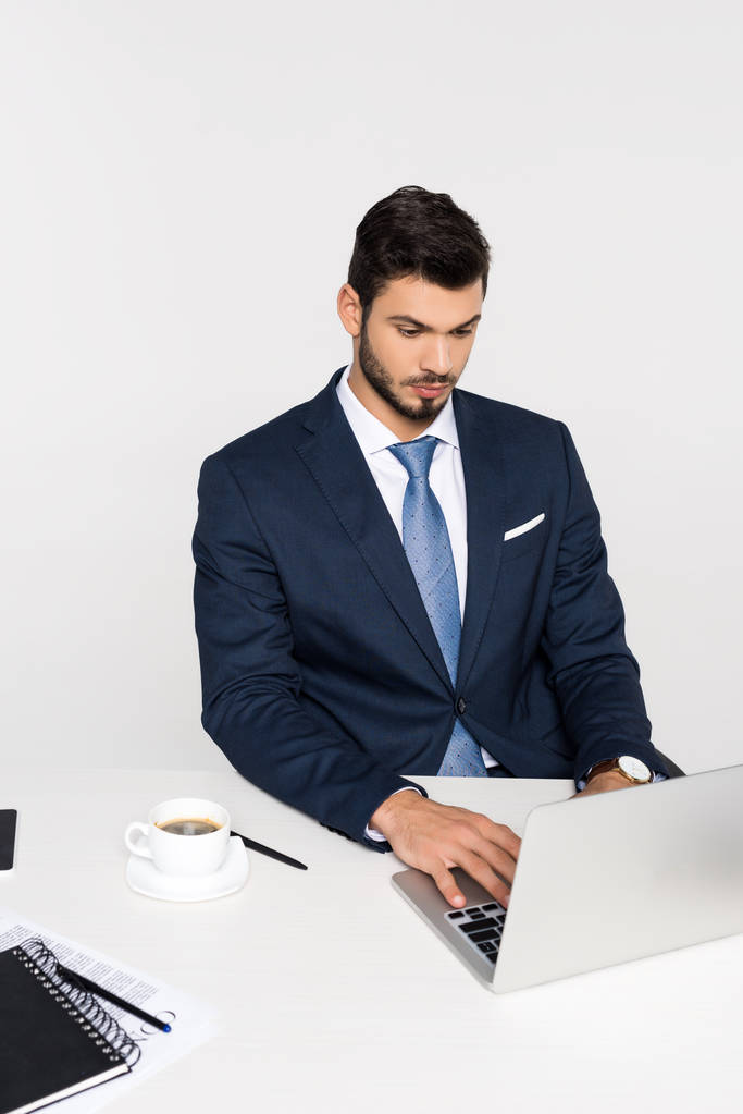 fiatal koncentrált üzletember használ laptop, és kávét iszik a munkahelyen - Fotó, kép