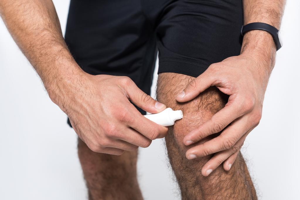 Oříznout záběr člověka aplikaci masti na kolena - Fotografie, Obrázek