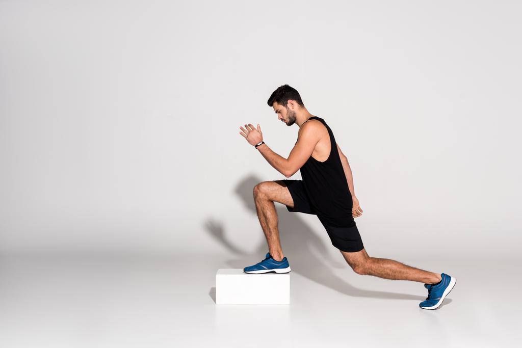 boční pohled na atletický muž dělá step aerobik na bloku - Fotografie, Obrázek