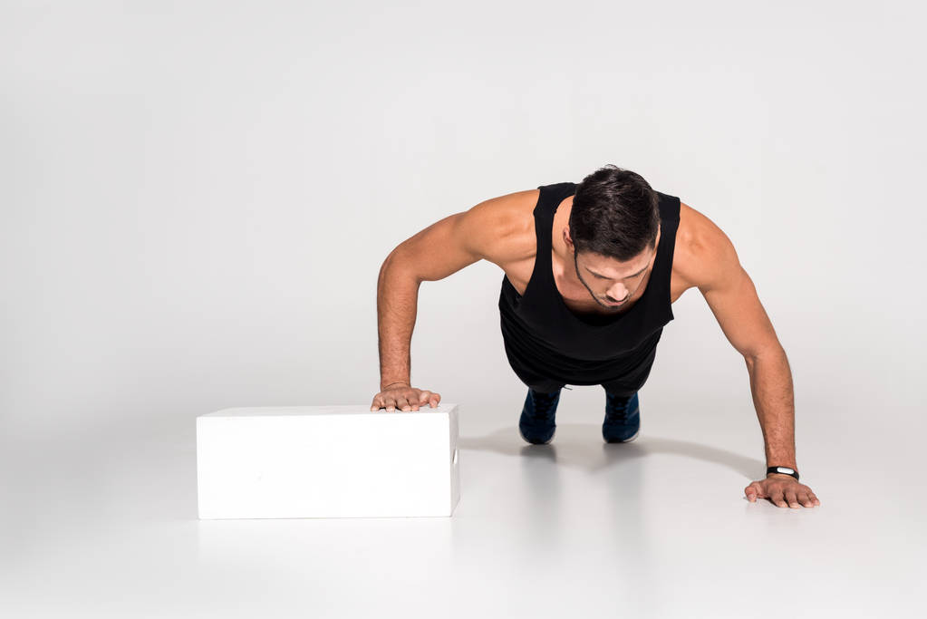 handsome young man doing push ups with one hand on block - Photo, Image