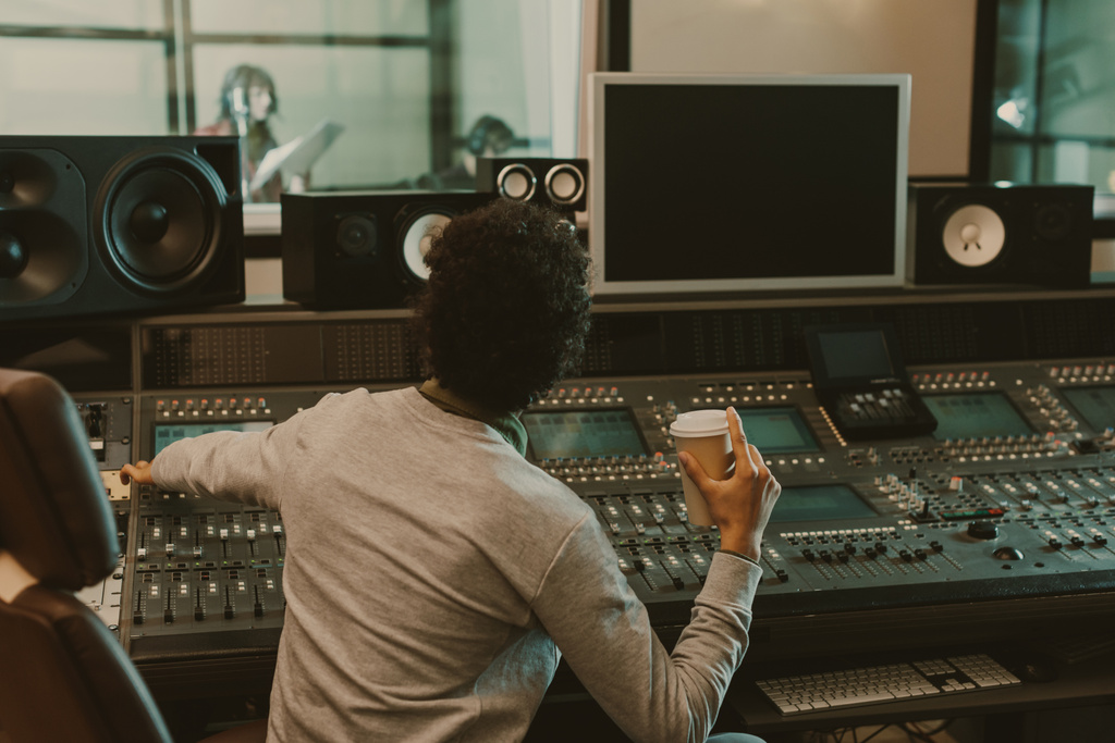 Звуковой продюсер с одноразовой чашкой кофе работает в студии
 - Фото, изображение
