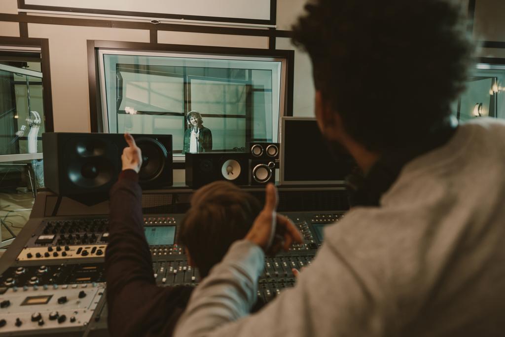 レコーディング スタジオで歌手に親指を示すサウンド プロデューサー - 写真・画像