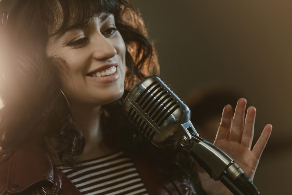привлекательная молодая певица, исполняющая песни и улыбающаяся
 - Фото, изображение