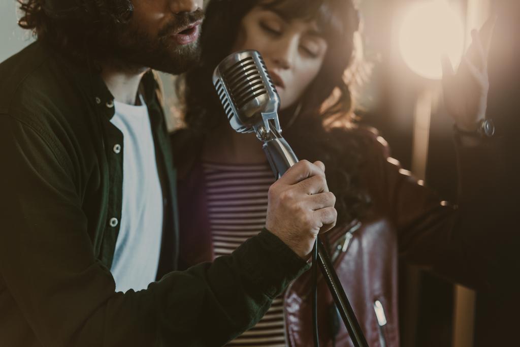 крупным планом молодая пара, исполняющая песню с винтажным микрофоном
 - Фото, изображение