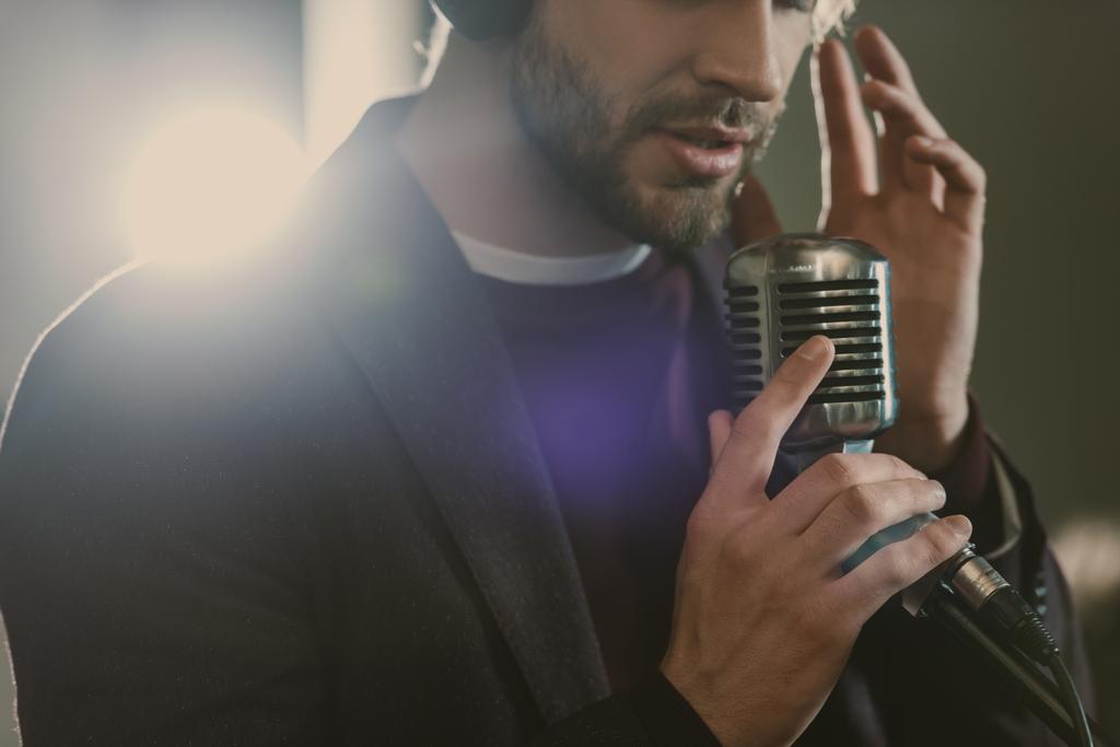 jovem cantor atraente em fones de ouvido cantando música no estúdio
 - Foto, Imagem