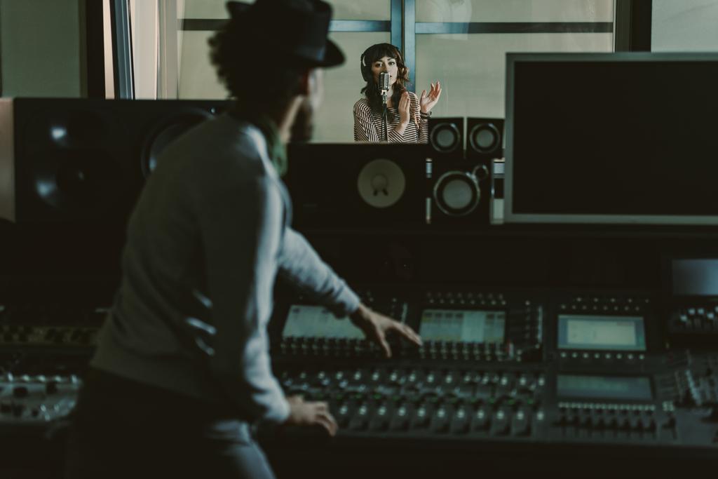 sound producer in hat recording song at dark studio - Photo, Image
