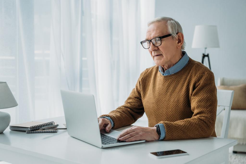 Uomo anziano fiducioso che lavora sul computer portatile
 - Foto, immagini